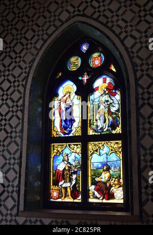 Stunning stained glass window on the wall in the palace of Pena, Sintra, Portugal. Colored pictures from the history of Portugal Stock Photo