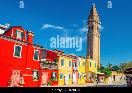 Bell tower campanile of San Martino Roman Catholic church and colorful houses in Burano island, blue sky in sunny summer day, Venice Province, Veneto Region, Northern Italy. Burano postcard Stock Photo