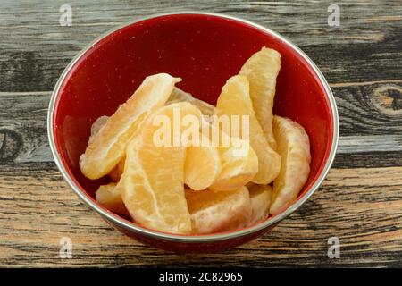 Fresh raw grapefruit sections in red breakfast bowl on table Stock Photo