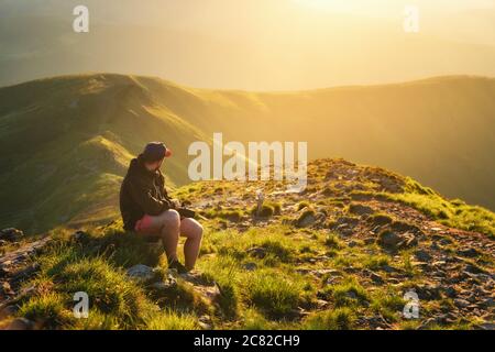 Beautiful mountains in fog and young man is sitting on the stone Stock Photo