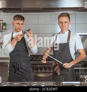 young chef sharpening knives in the kitchen Stock Photo