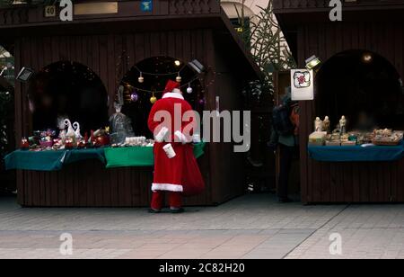 Krakow, Poland - December 23, 2014: A man dressed up as santa clause shopping in front of gift shop during christmas eve in city center main square Stock Photo