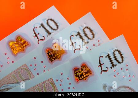 British pound sterling banknotes. Corners of 10 pound notes placed one on top of another on the vivid orage-red background. Stock Photo