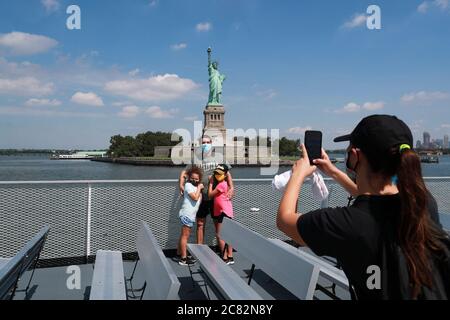 (200720) -- NEW YORK, July 20, 2020 (Xinhua) -- Visitors pose for photos with the Statue of Liberty on the cruise to Liberty Island in New York, the United States, July 20, 2020. New York City entered phase four of reopening on Monday without resuming additional indoor activities, as local officials are concerned about a potential second wave of coronavirus infections brought here from new hotspots across the country. The Liberty Island where the Statue of Liberty is located became open on Monday, while the interior of the statue and the museum remain closed to the public. (Xinhua/Wang Ying) Stock Photo