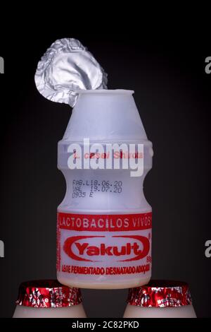 RIO DE JANEIRO, BRAZIL - Jul 01, 2020: Closeup of opened and empty small plastic bottle of Yakult with the lit still attached on top of two other bott Stock Photo