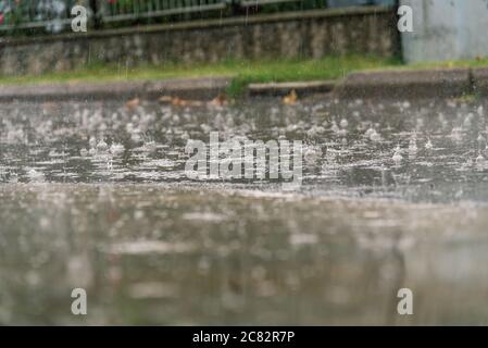 heavy rain drops falling on city asphalt during downpour in autumn Stock Photo