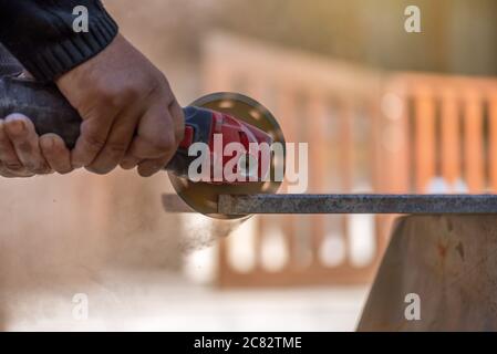 Grinder worker cuts stone block with electric hand saw. Stock Photo