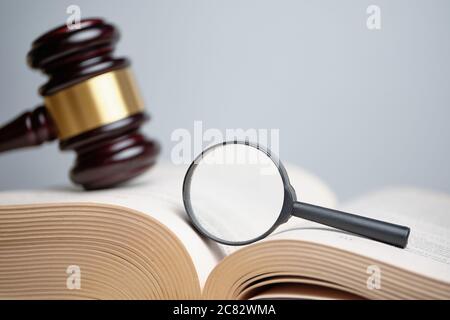 Judicial case investigation concept. The magnifying glass on the book next to the judge hammer Stock Photo