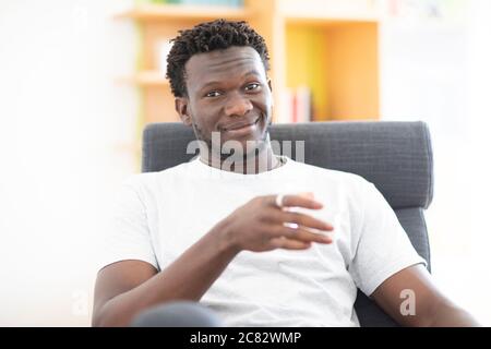 young man at home sitting  in an arm chair Stock Photo
