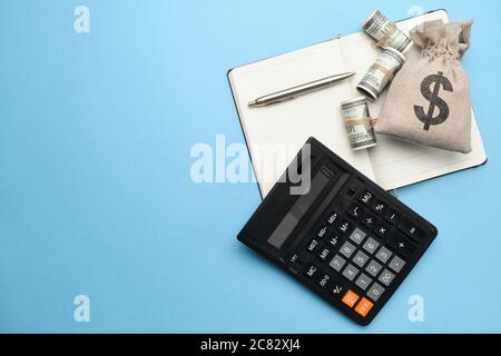 Abstract bag with money, calculator, pen and diary on a blue background with copy space Stock Photo