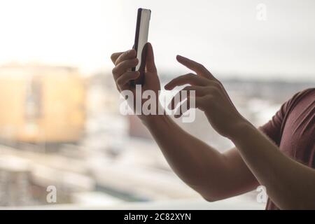 Man using his smartphone against a bright window Stock Photo