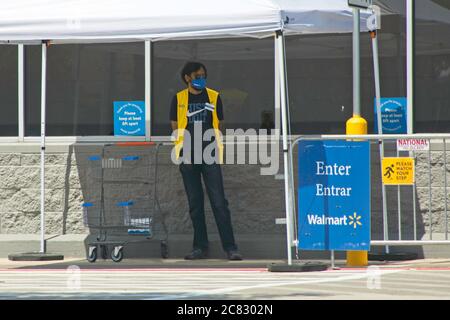 Plano, USA. 20th July, 2020. A Walmart Health Ambassador stands by the entrance to a Walmart store in Plano, Texas, the United States, on July 20, 2020. The world's largest retailer Walmart has announced that Walmart and Sam's Club shoppers in the United States will be required to wear face coverings starting July 20. In addition to posting clear signs at the front of stores, Walmart has created the role of Health Ambassador and will station them near the entrance to remind those without a mask. Credit: Dan Tian/Xinhua/Alamy Live News Stock Photo