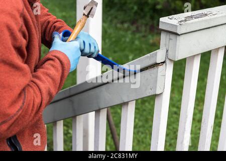 Man Using a Hammer and Pry Bar to Tear Down Old Deck Stock Photo