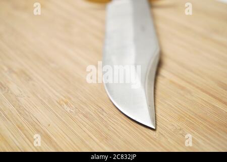 Closeup shot of a knife blade on the wooden table Stock Photo