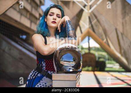 Attractive and beautiful woman with blue hair, leaning on the motorcycle helmet Stock Photo