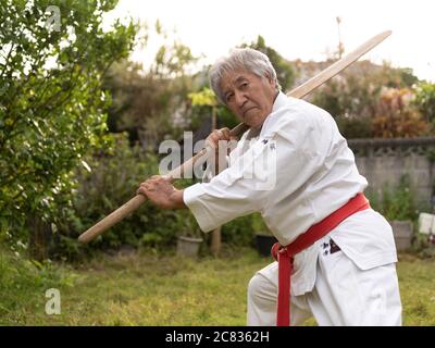 Kenyu Chinen Sensei of the World Oshukai Okinawa Shorin-Ryu Karate Do Kobudo Federation training with eku (oar) at his home in Ogimi Village, Okinawa Stock Photo