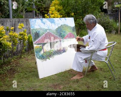 Kenyu Chinen Sensei of the World Oshukai Okinawa Shorin-Ryu Karate Do Kobudo Federation taking a break from karate training by painting at his home in Stock Photo
