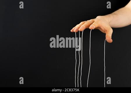 puppeteer's hand with ropes on fingers control the people mind concept ...