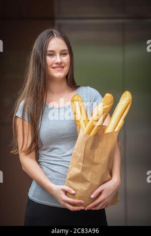 Woman receiving food package from delivery service company staff at home. Delivery and shopping online concept. Stock Photo