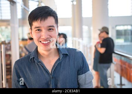 Portrait of young and handsome student smiling with friends in campus. Casual outfit of asian male in school. Stock Photo