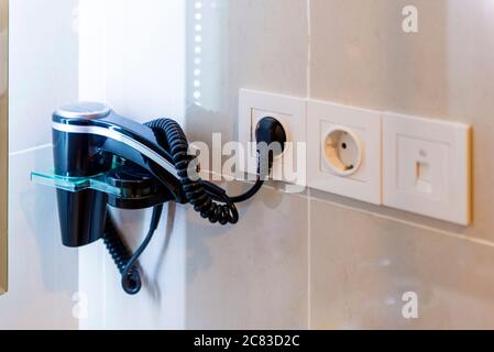 Close up view of hairdryer hanging in the wall Stock Photo