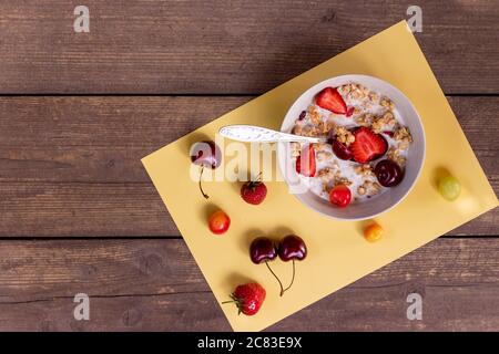Delicious Yogurt with granola and fresh berries, in bowl over old wood background.Cereals breakfast. Healthy morning meal with fresh strawberries Stock Photo
