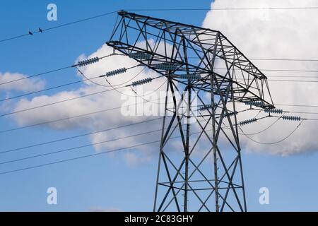 High voltage electricity pylon, at blue sky with clouds. Two birds are on the electricity cable Stock Photo