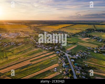 Amazing aerial countryside landscape. Sunset over green and yellow fields and small villages. Stock Photo