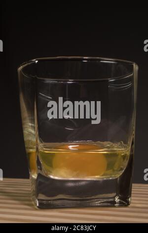 Raw egg in a glass beaker. On a black background Stock Photo