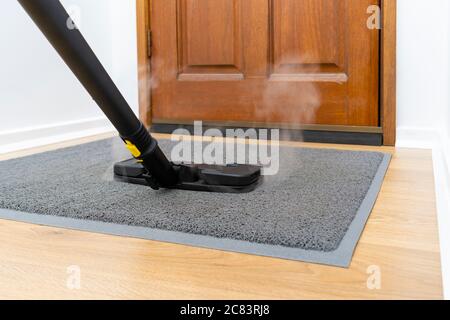 Sanitizing front doormat with steam cleaner Stock Photo