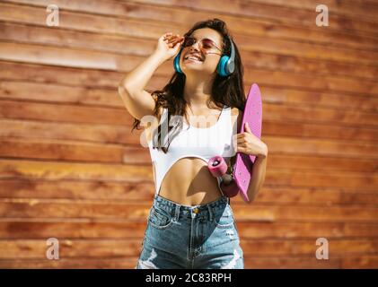 Beautiful brunette girl with skateboard feeling enjoyed Stock Photo