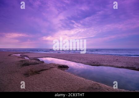 Seascape, sunset over the sea. The river flows into the sea. Atlantic ocean in evening, beautiful nature, sandy beach