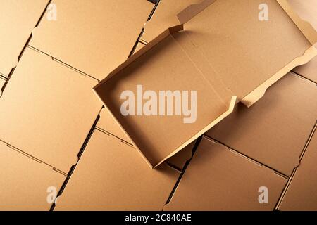 Unused open empty brown cardboard pizza box on top of a layer of closed unlabelled generic boxes in a full frame view Stock Photo