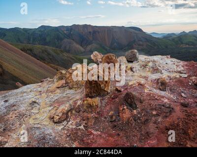 Colorful rhyolit red and orange fumarole at foot of Brennisteinsalda mountain with panorma of Landmannalaugar. Area of Fjallabak Nature Reserve in Stock Photo