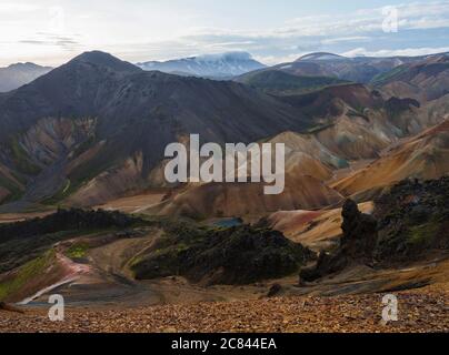 Colorful Rhyolit rainbow mountain panorma with multicolored volcanos and geothermal lake and snow covered peaks. Sunrise in Landmannalaugar at Stock Photo