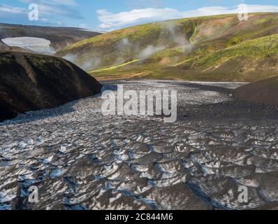 Snow field at Landmannalaugar colorful Rhyolit mountains with steam from hot spring on famous Laugavegur trek. Fjallabak Nature Reserve in Highlands Stock Photo