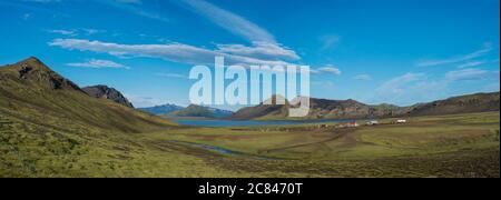 Panoramic landscape with mountain huts at camping site on blue Alftavatn lake with river, green hills and glacier in beautiful landscape of the Stock Photo