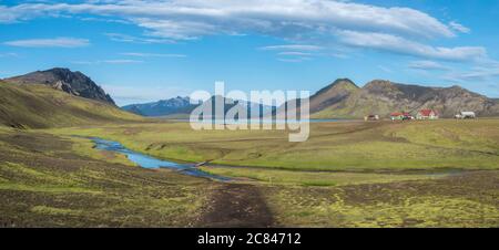 Panoramic landscape with mountain huts at camping site on blue Alftavatn lake with river, green hills and glacier in beautiful landscape of the Stock Photo