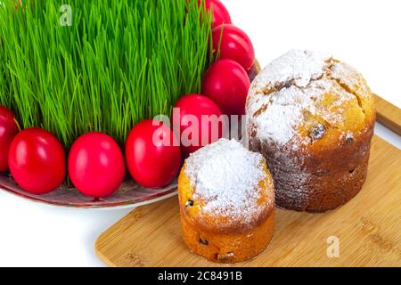 Red Easter eggs around wheat grass on the plate isolated on white, Ester cake Stock Photo