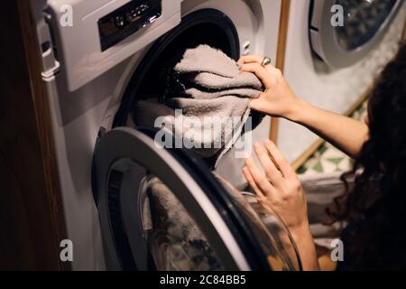 Close up girl taking out clothes from washing machine in self-service laundry Stock Photo