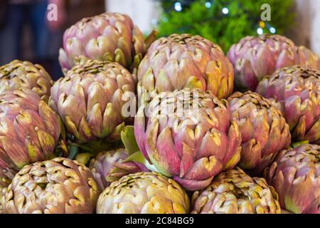 Fresh big Romanesco artichokes, green purple flower heads on a market place. Stock Photo