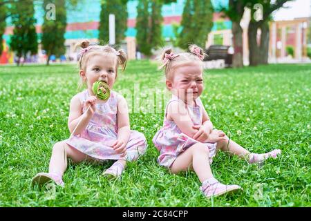 a little girl is crying because they didn't give her candy. Twins Stock Photo