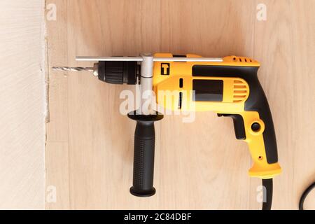 Drilling a hole in the wall with drill. Repair and construction in the house Stock Photo