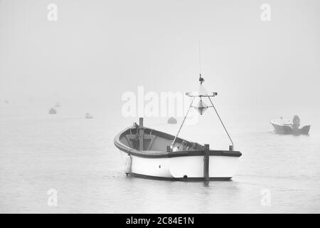 Heavy fog rolling in off of the North Sea, up the River Ore enveloping a small boat in Orford harbour. This photograph was taken from Orford Quay earl Stock Photo