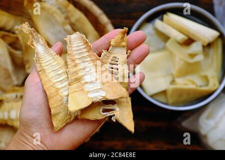 Top view close up woman hand hold dried bamboo shoots on bamboo background, raw material for many Vietnamese vegan food Stock Photo