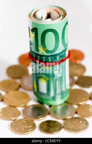 banknotes rolled up in a tube and scattered change next to them Stock Photo