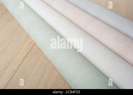 several rolls of multi-colored paper wallpaper on a wooden table Stock Photo