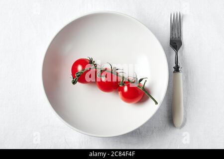 Fresh red cherry tomatoes on a white plate. Stock Photo