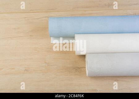 several rolls of multi-colored paper wallpaper on a wooden table Stock Photo