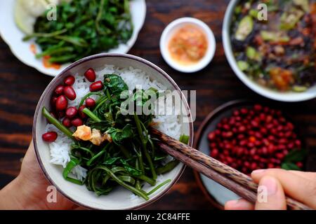 Top view close up people have lunch, hand hold rice bowl with Vietnamese vegan food background, fried peanut, seaweed soup, dish good for health Stock Photo